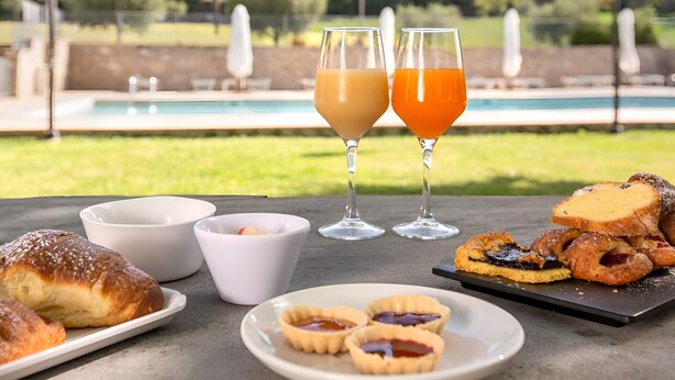 A table with food and drinks, a pool, and a view of trees and hills. - Catignano Hotel (Gubbio)
