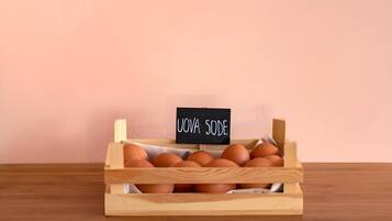 A wooden crate with eggs labeled "UOVA SODE" on a wooden table against a pink wall.