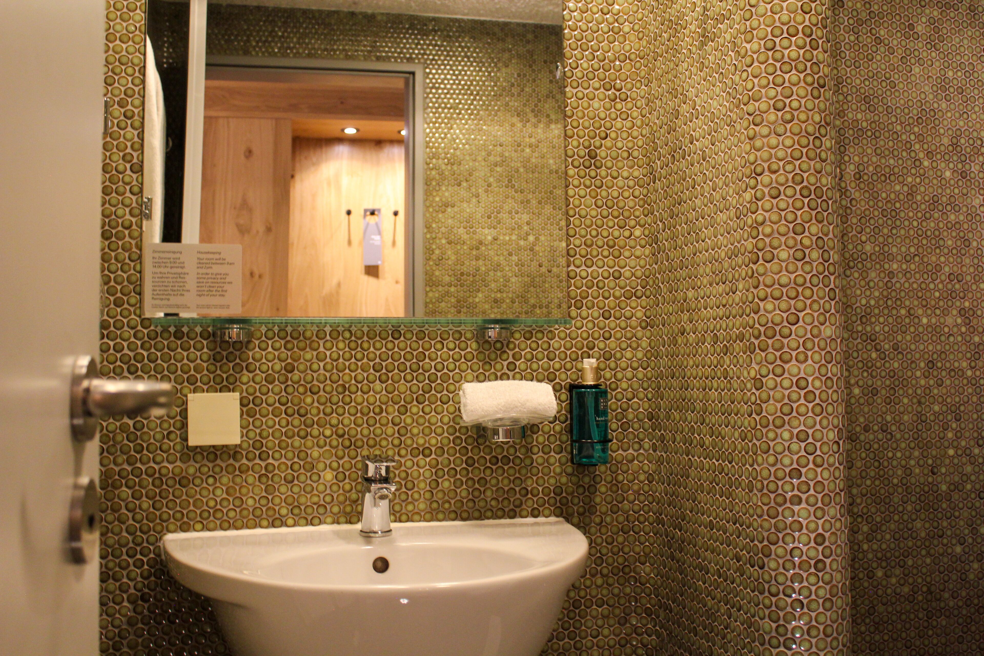 Ein Badezimmer mit Waschbecken, Spiegel und Handtuchspender.