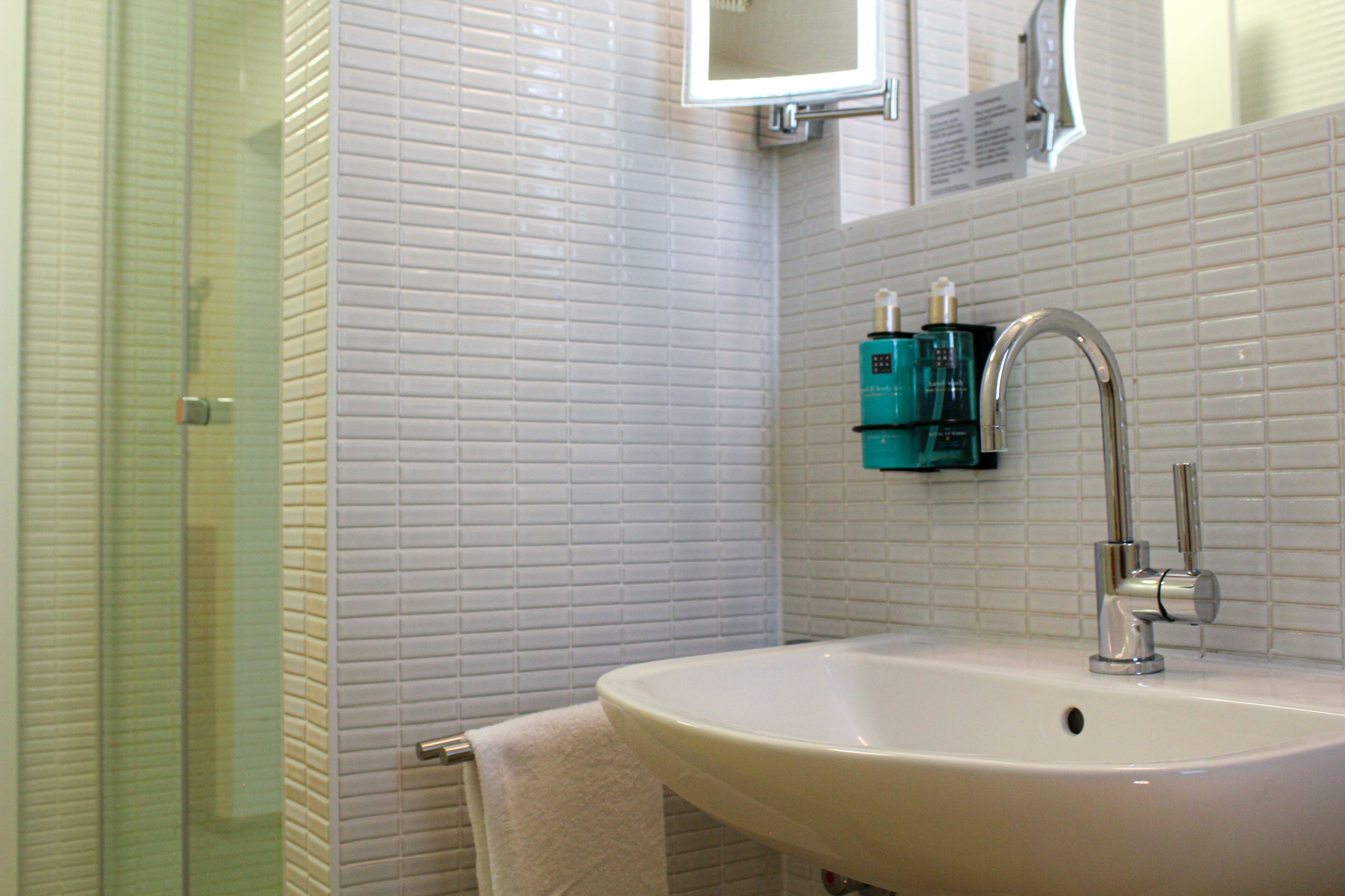 A bathroom with a white sink, a glass shower enclosure, and a mirror above the sink.