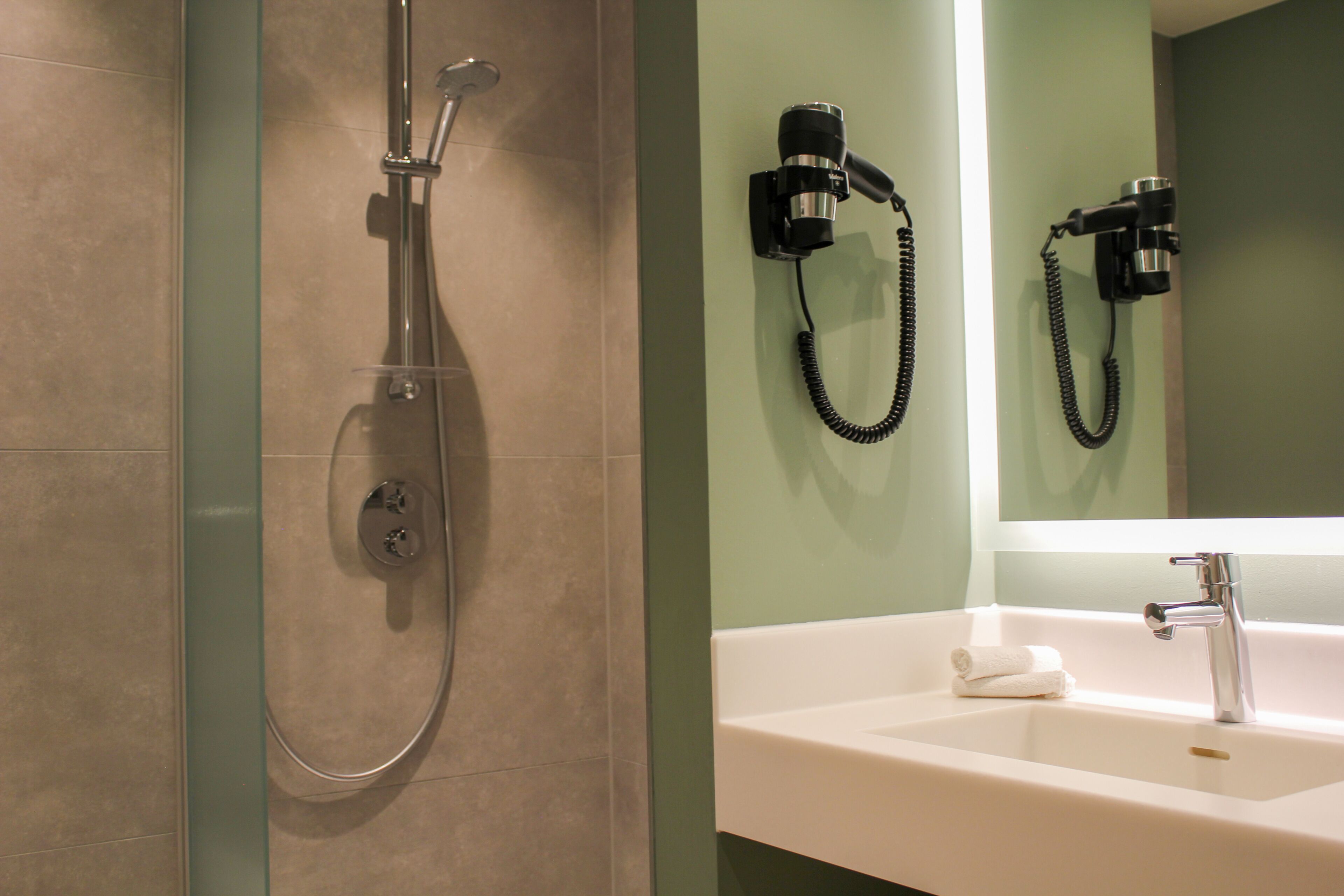 Une salle de bain avec une douche, un lavabo et un miroir.