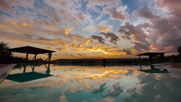 A serene outdoor pool area with a clear sky and sunset reflection.