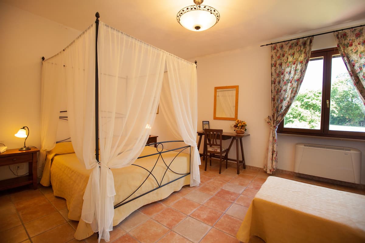 A bedroom with a four-poster bed, a desk, and a chair.