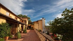 A courtyard with a brick pathway, stone walls, and potted plants.