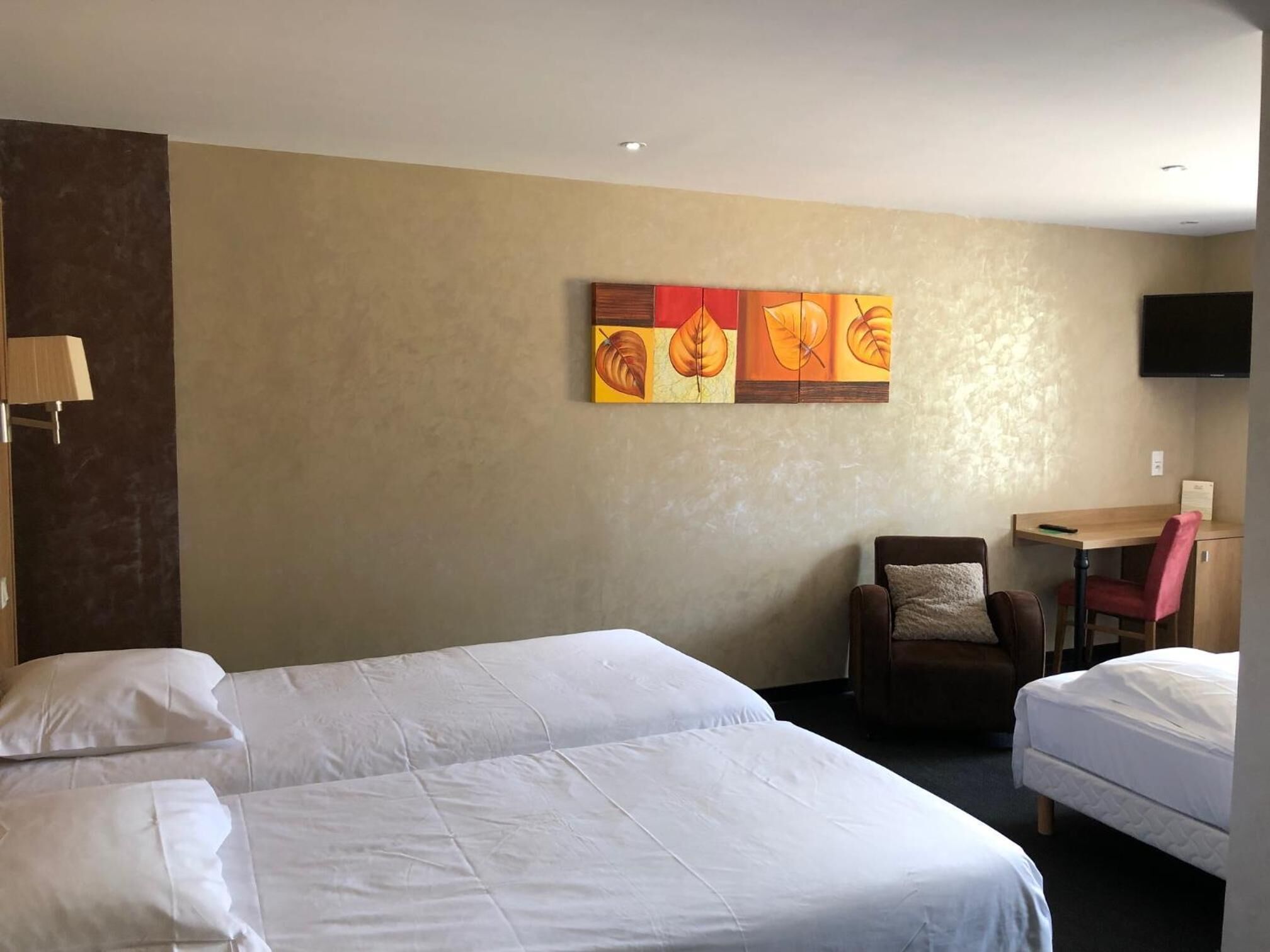Camera d'albergo con due letti, una scrivania, una sedia e la televisione a parete.