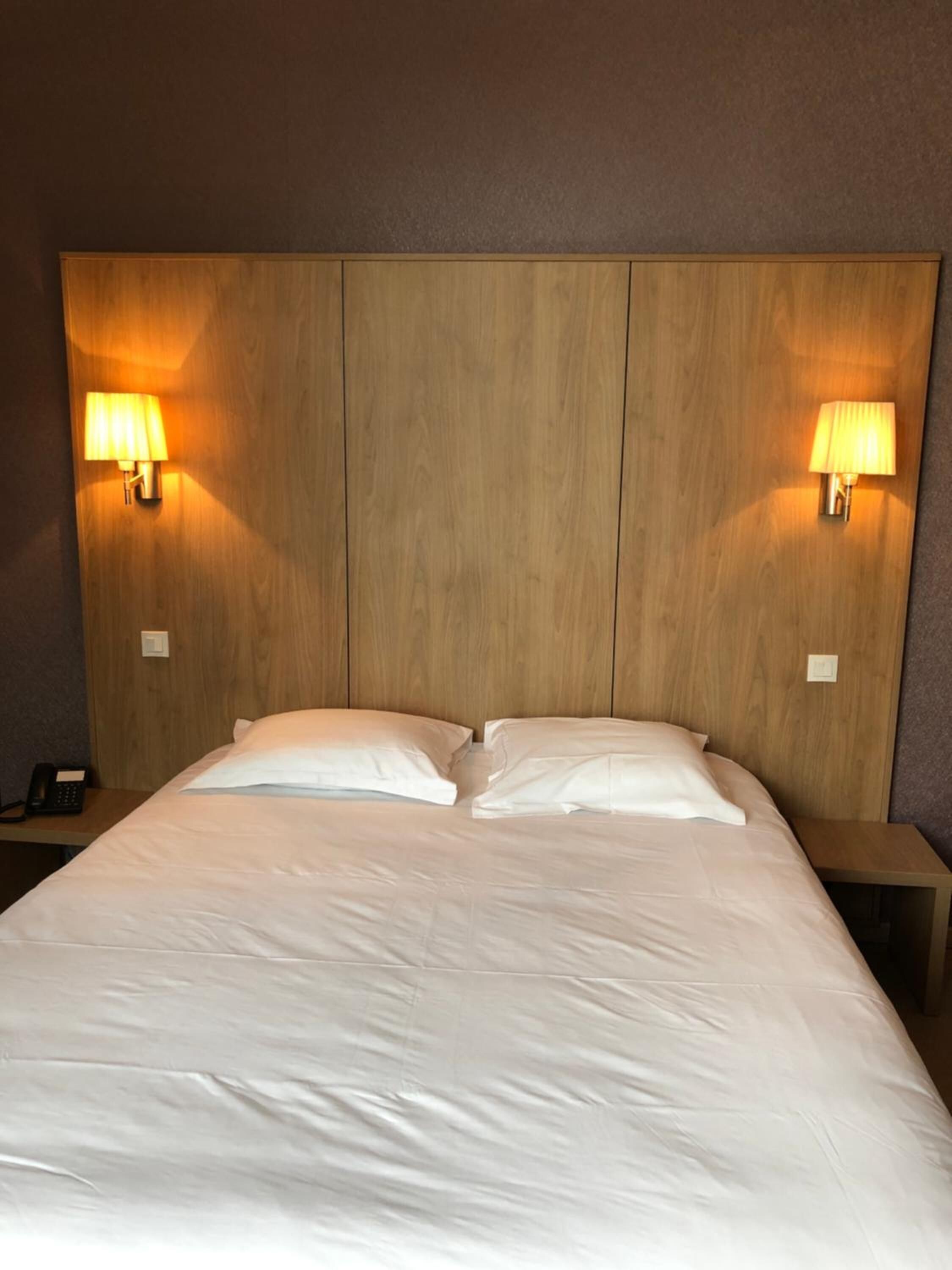 Une chambre d’hôtel avec un grand lit, deux lampes de chevet et une table de chevet avec un téléphone.
