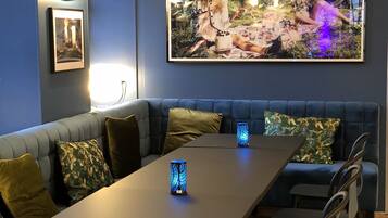 A modern living room with a sectional sofa, a dining table, and a large framed picture on the wall.