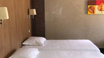 A hotel room with a large bed, two bedside lamps, a wooden headboard, and a wall painting.