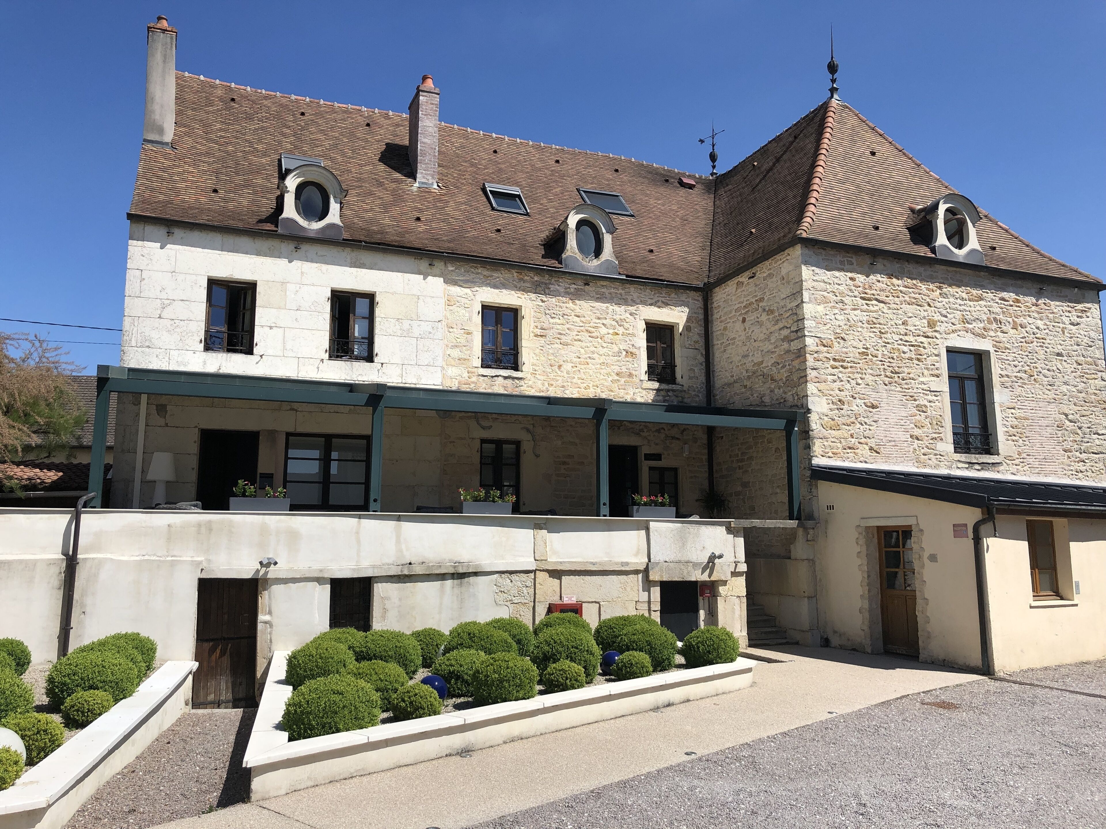 Un bâtiment en pierre de deux étages, doté d’un balcon et d’une entrée couverte.