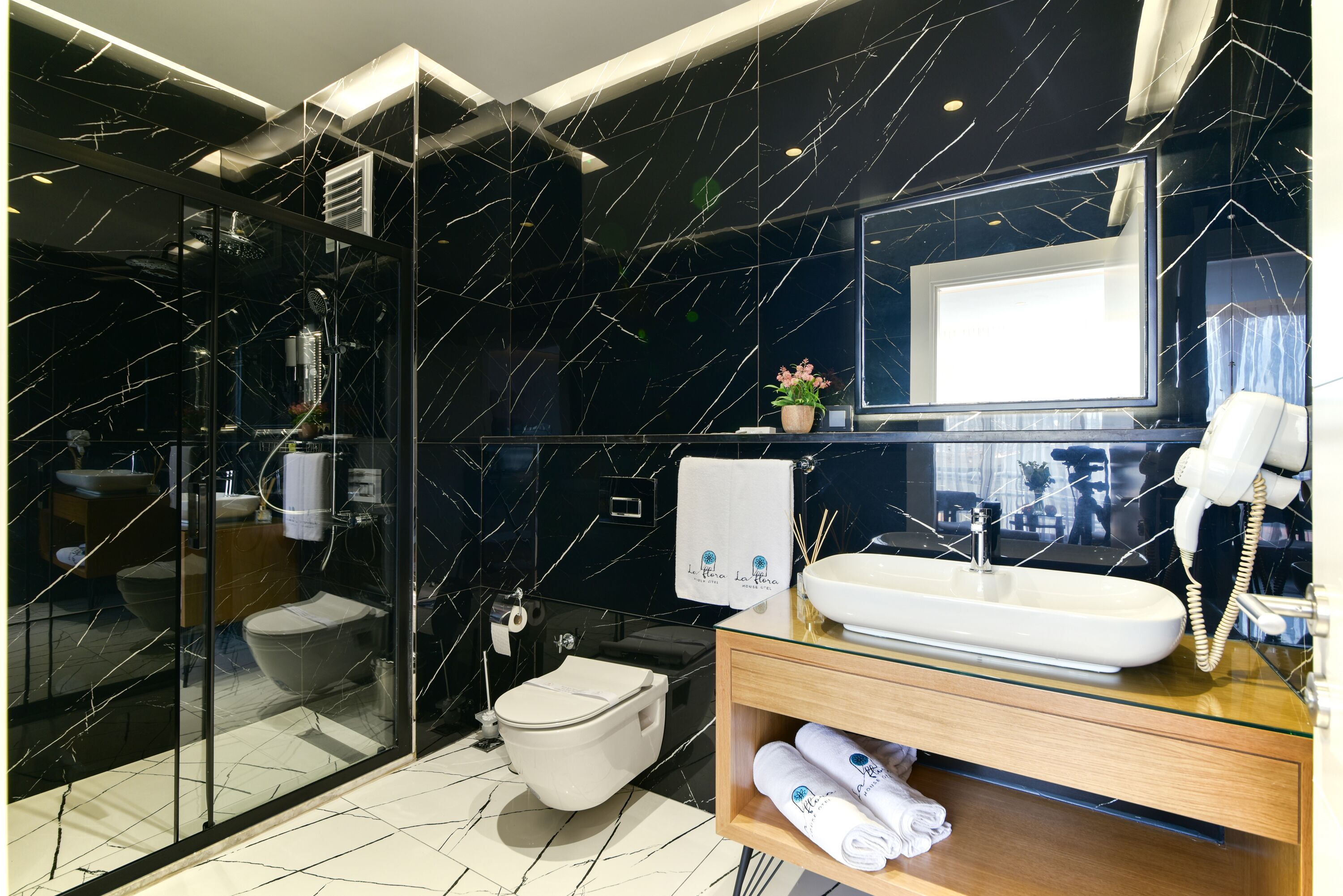 Un baño moderno con cabina de ducha de vidrio, inodoro, lavabo con espejo y teléfono.