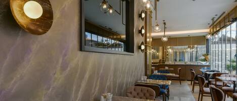 Un interior de restaurante moderno con suelo de mármol, mesas de madera e iluminación contemporánea.