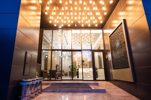 A hotel entrance with a modern design, featuring a glass door, a reception area with seating, and a decorative wall. - La Flora House Otel (Izmit)
