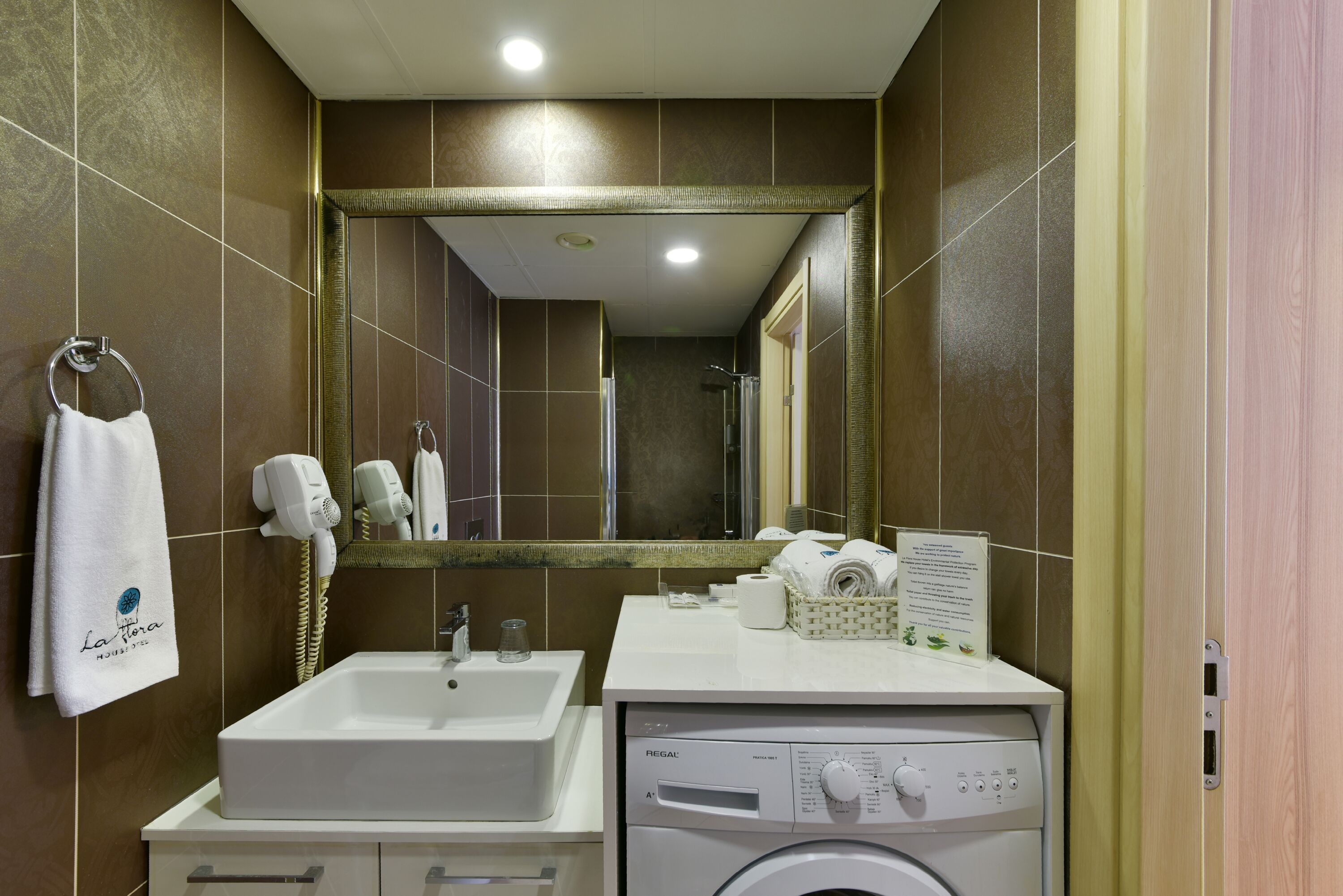A bathroom with a sink, mirror, towel rack, hairdryer, and a washing machine.