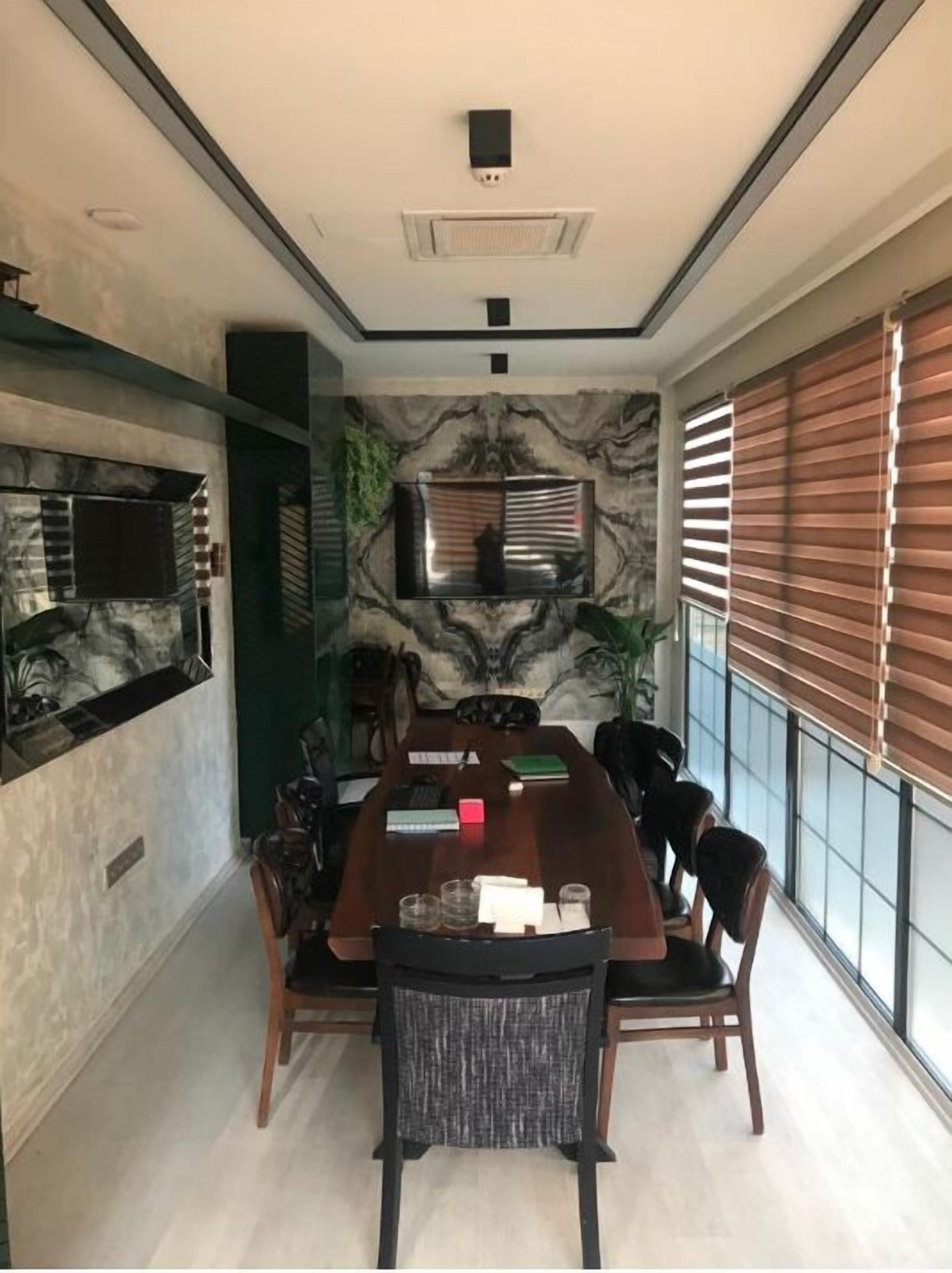 Un comedor moderno con una gran mesa de madera, seis sillas, un televisor de pantalla plana en la pared y un panel decorativo.