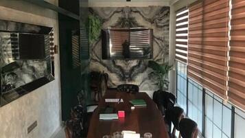 Un comedor moderno con una gran mesa de madera, seis sillas, un televisor de pantalla plana en la pared y un panel decorativo.