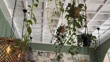 A restaurant interior with hanging plants, a map mural, and tables set for dining.