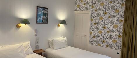 A room with two beds, a wall-mounted telephone, and a painting.