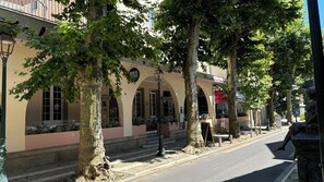 Eine von Bäumen gesäumte Straße mit einem Gebäude, das ein Schild für das 'Hotel de Lyon Restaurant' zeigt.