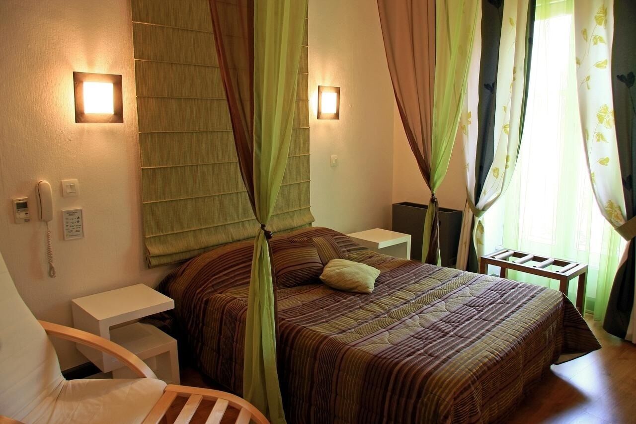 A bedroom with a bed, bedside tables, a chair, and curtains.