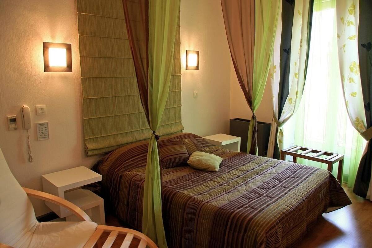 A bedroom with a bed, bedside tables, a chair, and curtains.