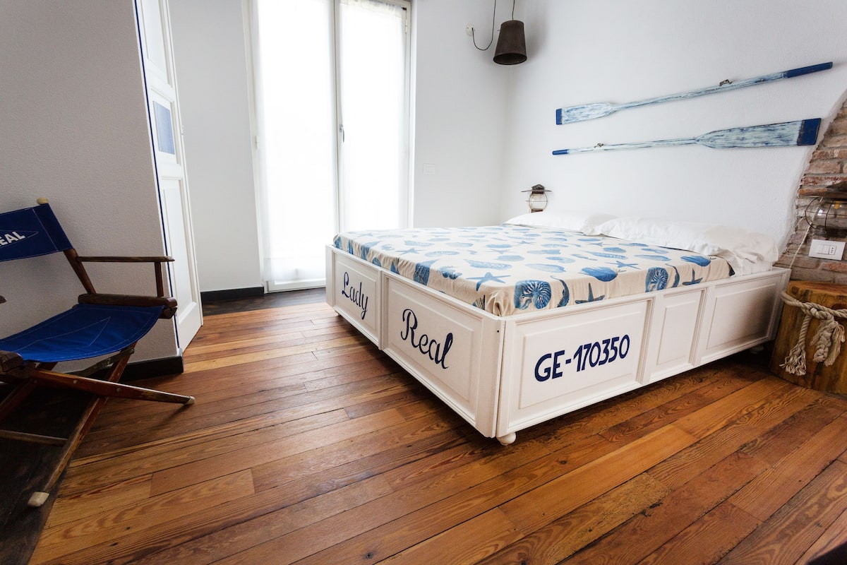 A bedroom with a wooden floor, a bed with 'Lady Real' and 'GE-170350' branding, a blue chair, and a brick wall.