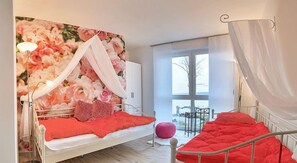 Une chambre à coucher avec un lit, une table de chevet, une fenêtre et une vue sur l’extérieur.