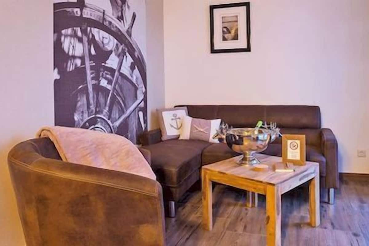 Een woonkamer met een bruine leren bank, een houten salontafel en een groot abstract schilderij aan de muur.