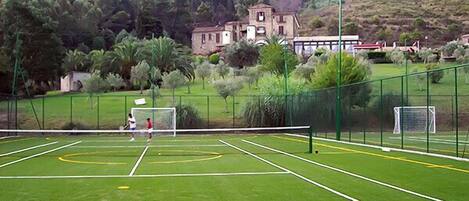 A soccer field with goalposts, surrounded by a fence and greenery.