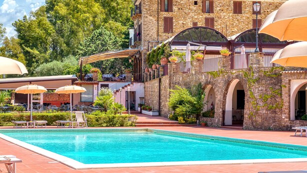 A pool area with a stone building, outdoor seating, and a clear blue sky. - Hotel Hermitage (Castellabate)