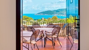 A terrace with outdoor seating and a scenic view of the sea and hills. - Hotel Hermitage (Castellabate)