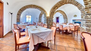 A dining area with stone arches, tables set with white tablecloths, and chairs. - Hotel Hermitage (Castellabate)