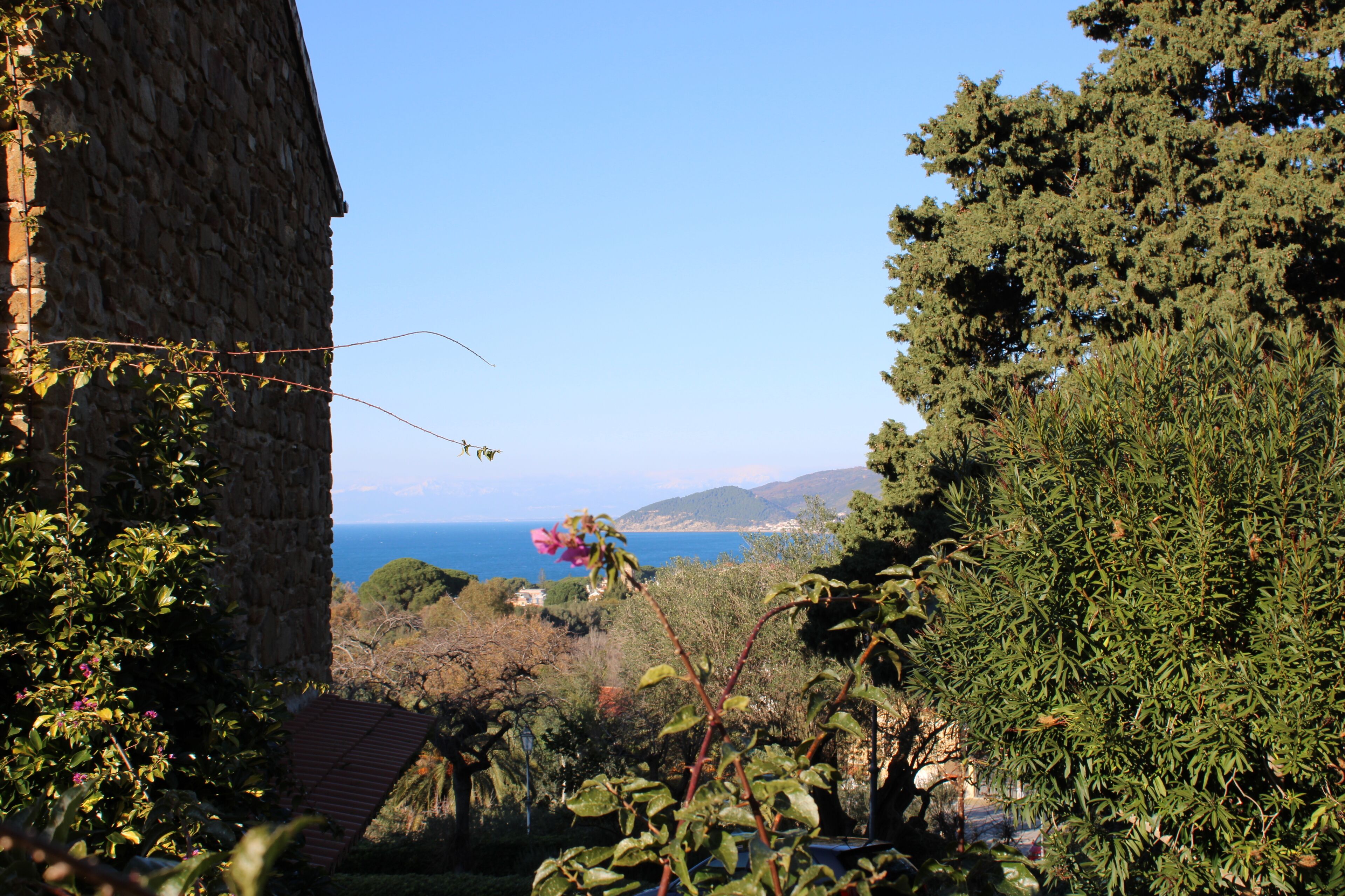 A stone building with a view of the sea and hills.