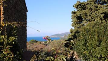 A stone building with a view of the sea and hills.