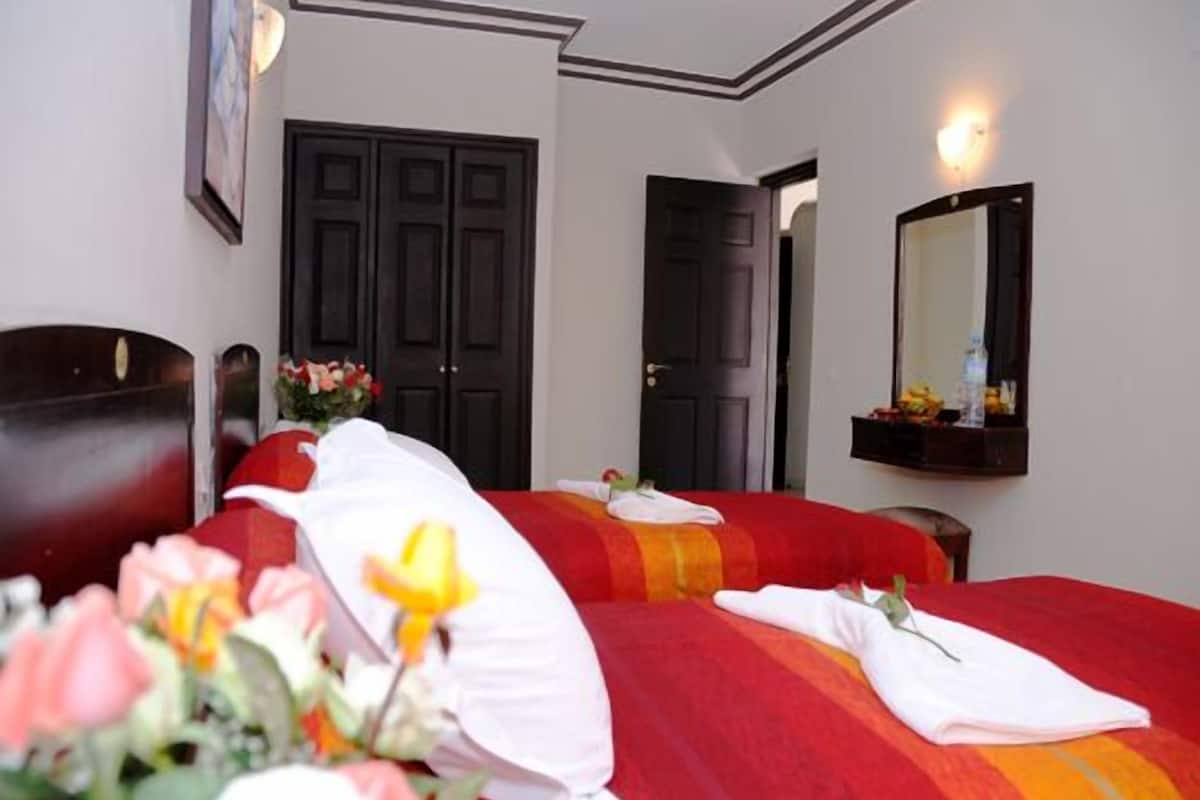 A hotel room with two beds, a large mirror, and a door leading to another room.