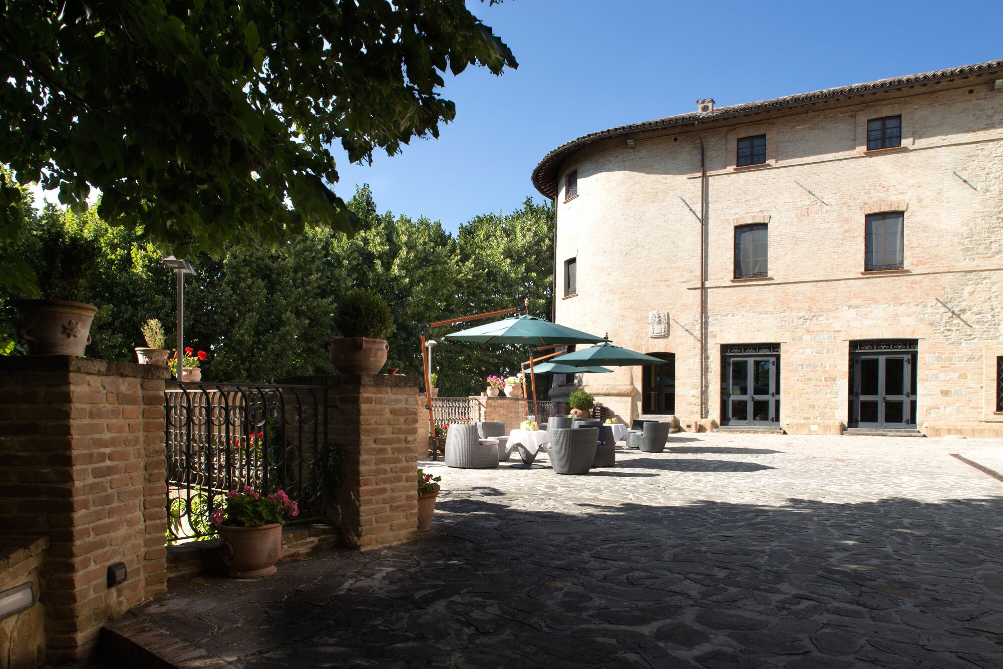 A courtyard with outdoor seating, a brick building, and potted plants.