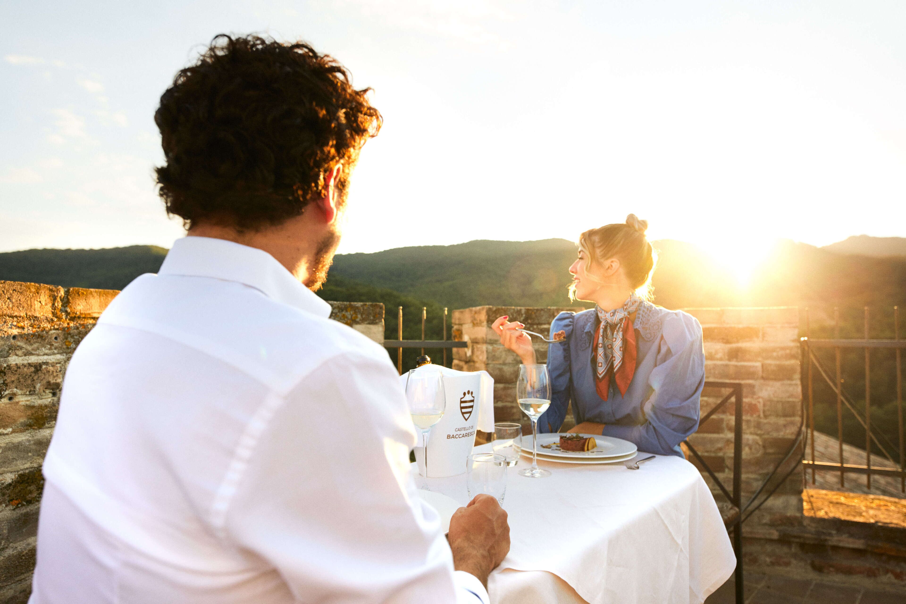 A couple dining at a table with a view of the countryside.