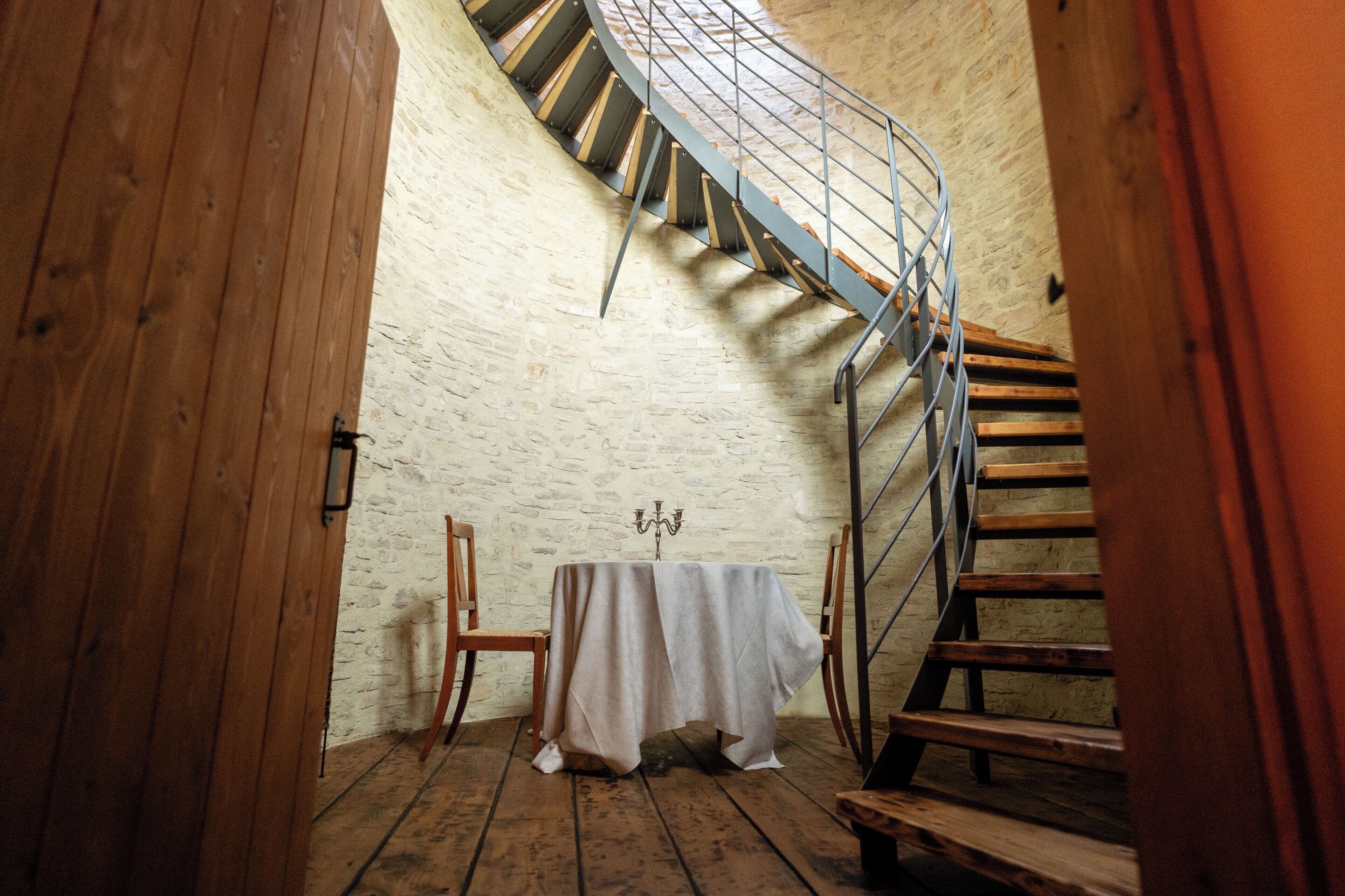 A spiral staircase in a room with a wooden floor and a table with a tablecloth.