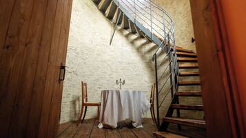 A spiral staircase in a room with a wooden floor and a table with a tablecloth.