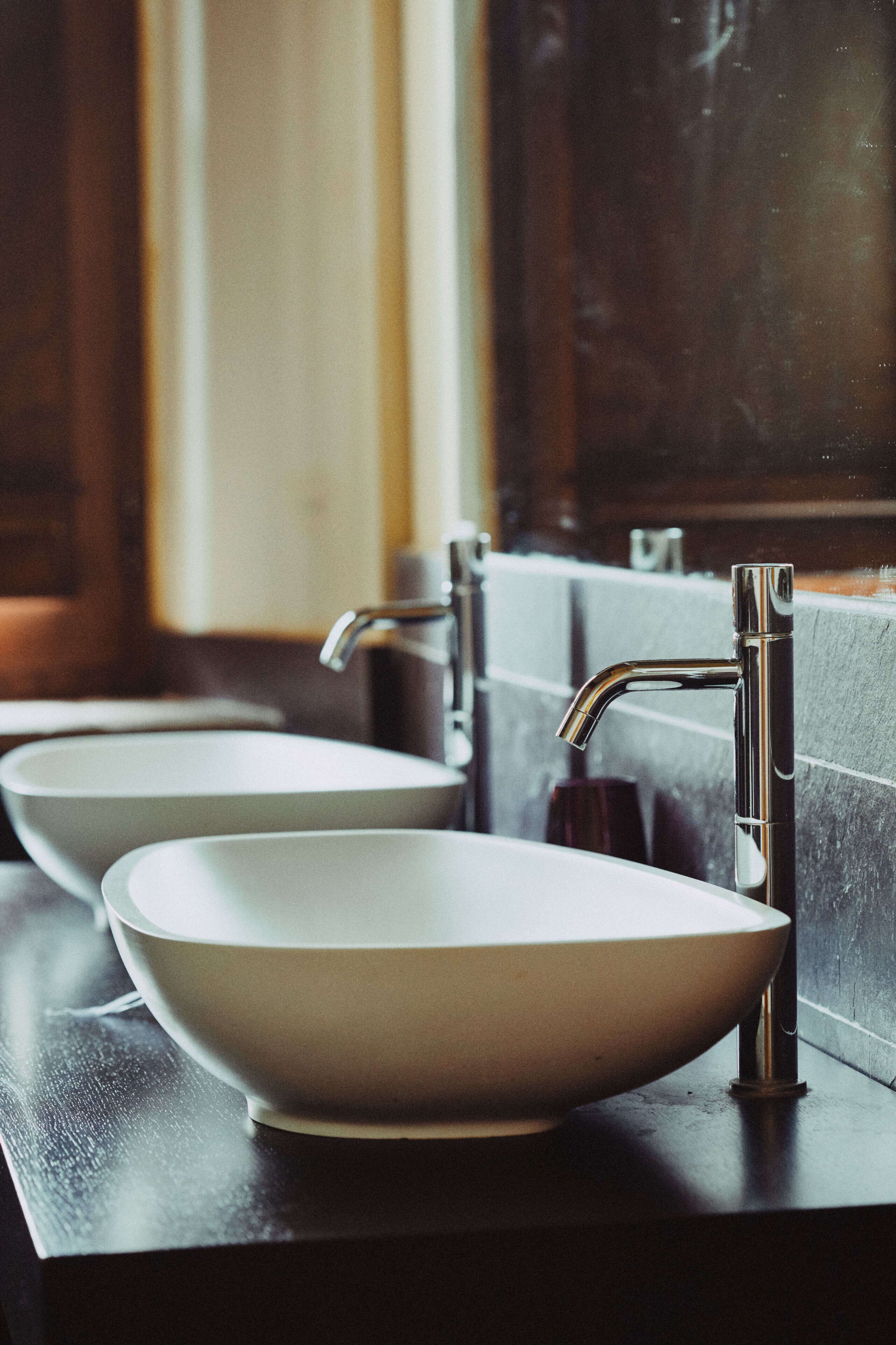 A bathroom with three white sinks and modern faucets.