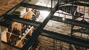 Un espacio interior con paredes de piedra, mesas dispuestas para una recepción y una presentación de vinos.