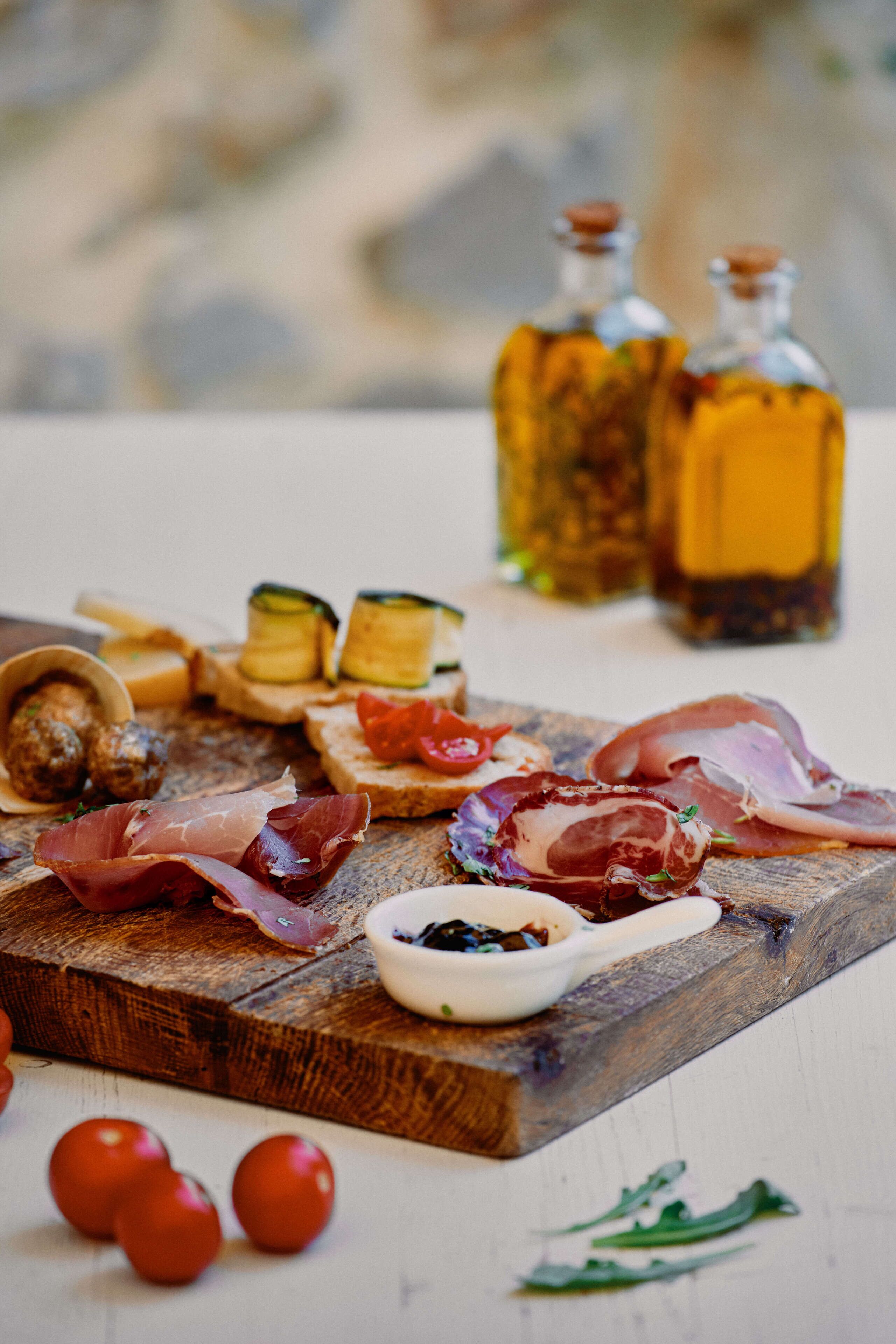 Ein Holzbrett mit verschiedenen Speisen, darunter Fleisch, Käse und Gemüse.