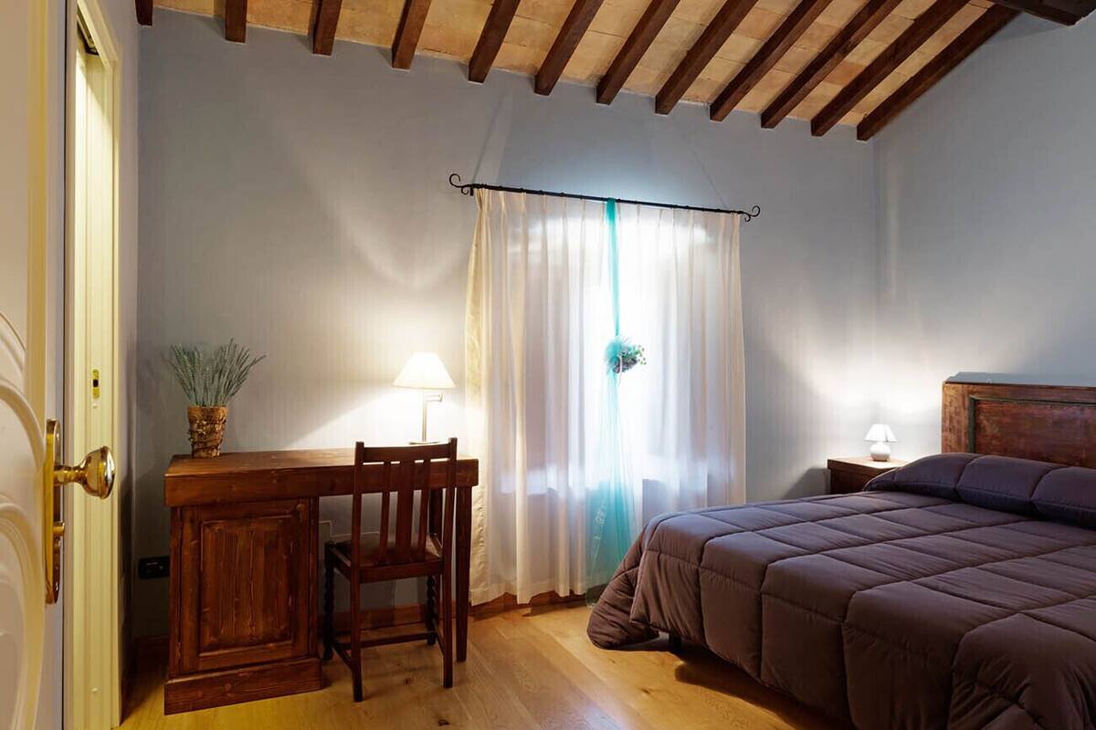 A bedroom with a wooden desk, chair, and a bed with a headboard.