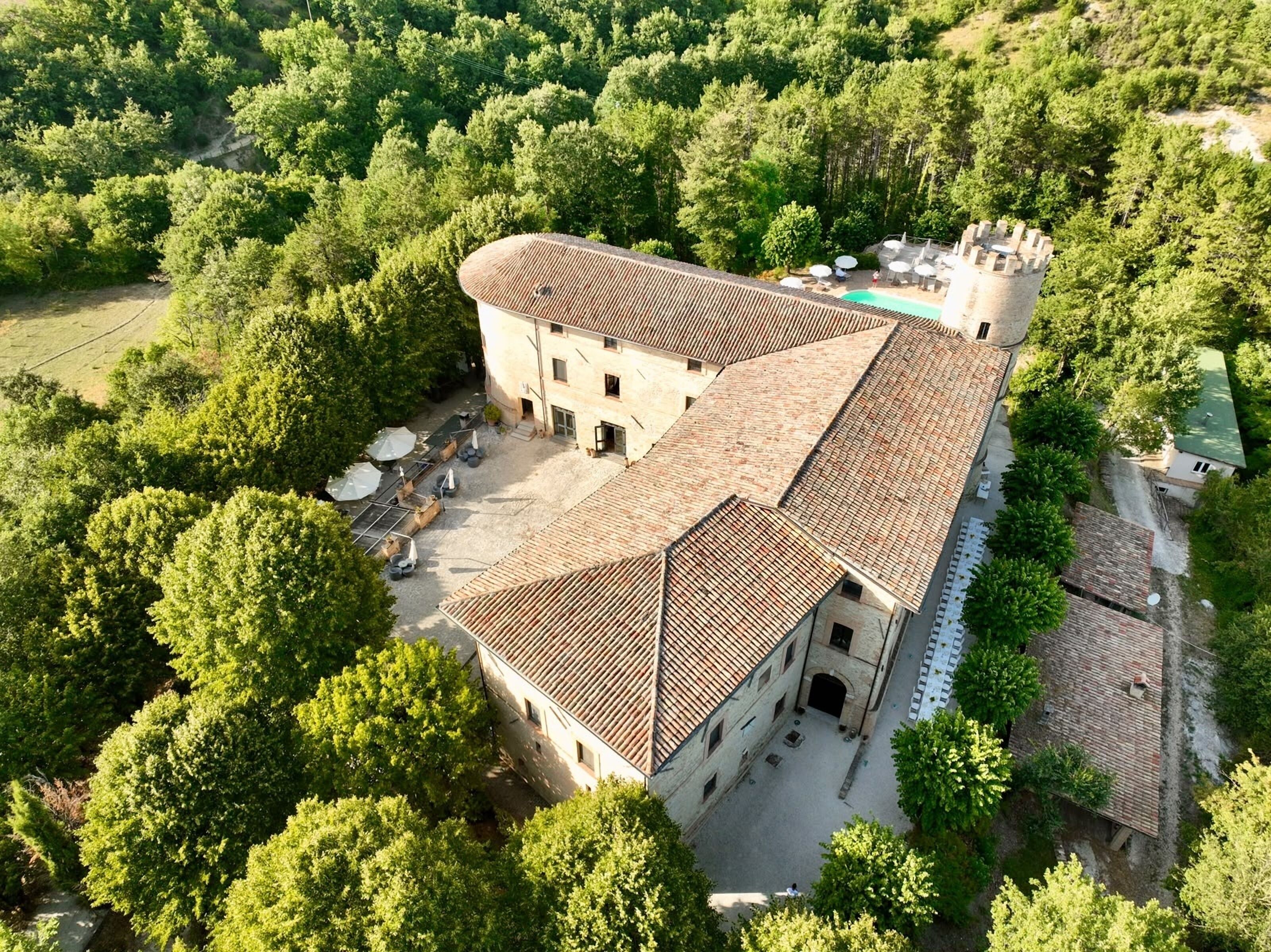 Un edificio grande con un cortile interno, circondato da alberi rigogliosi.