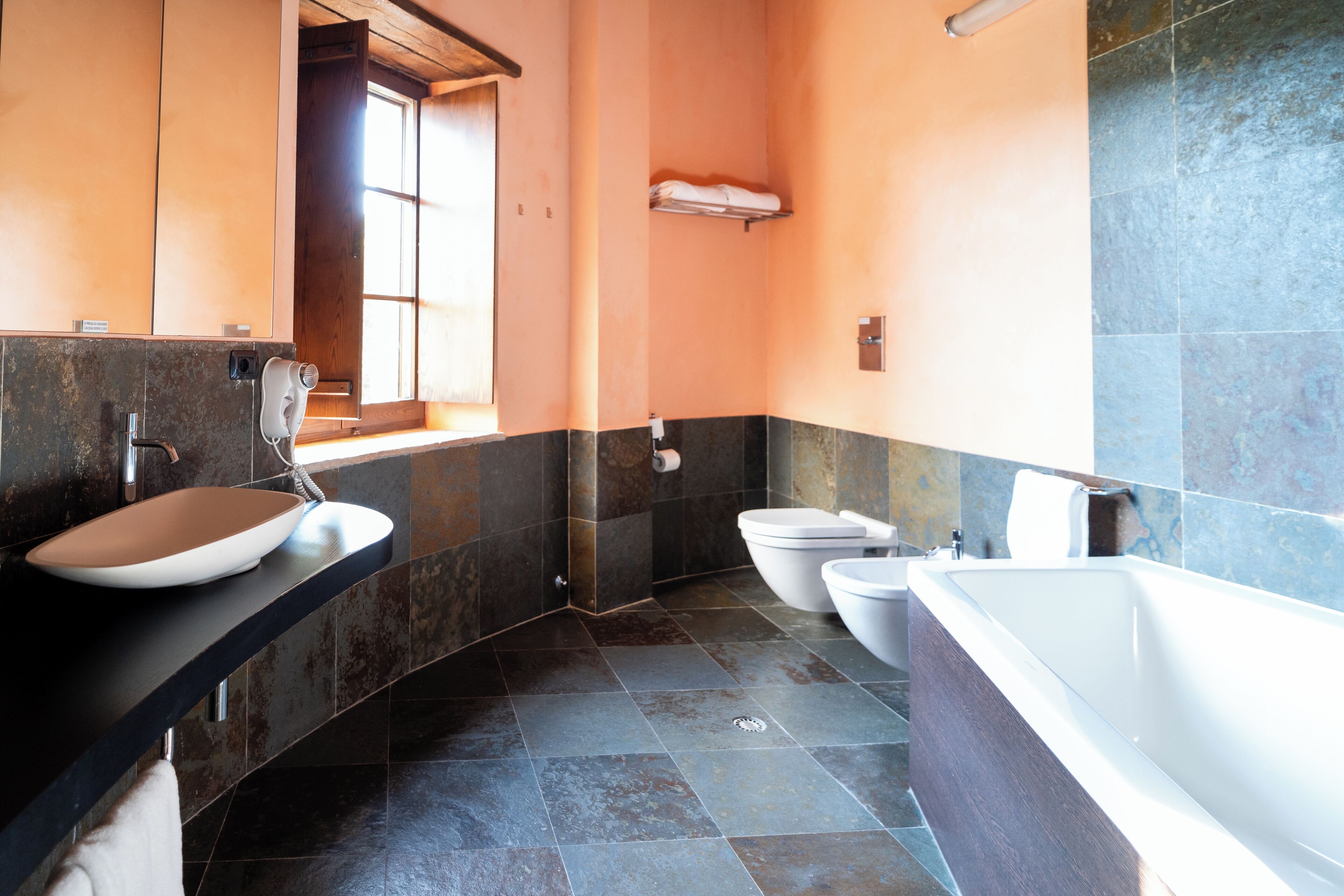 A modern bathroom with a large bathtub, a sink, and two toilets.