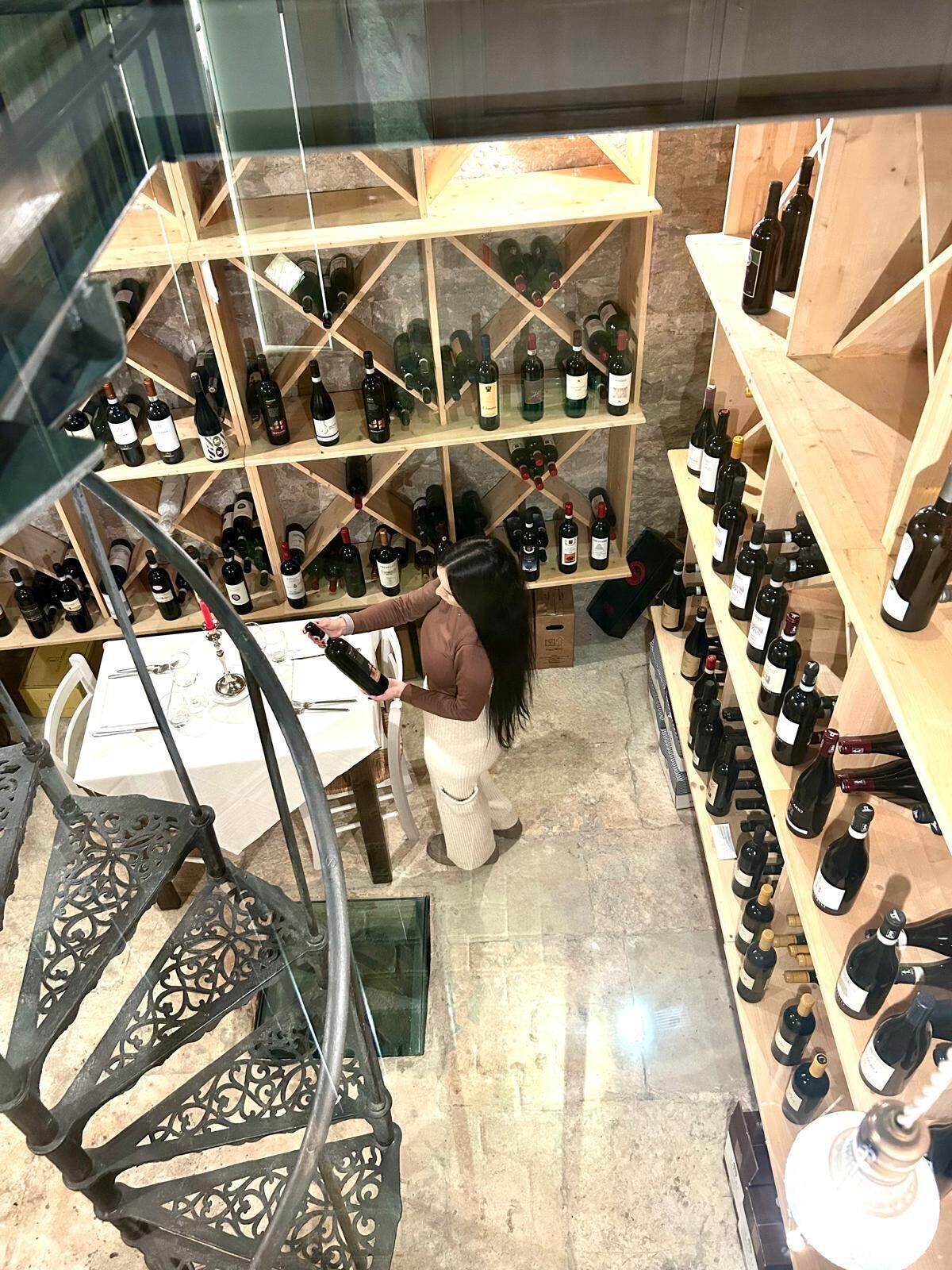 A wine cellar with wooden shelves stocked with wine bottles.