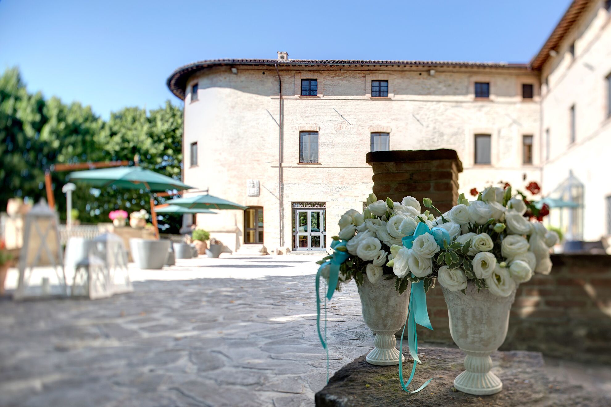 A courtyard with stone flooring, outdoor seating, and a building with multiple windows in the background.