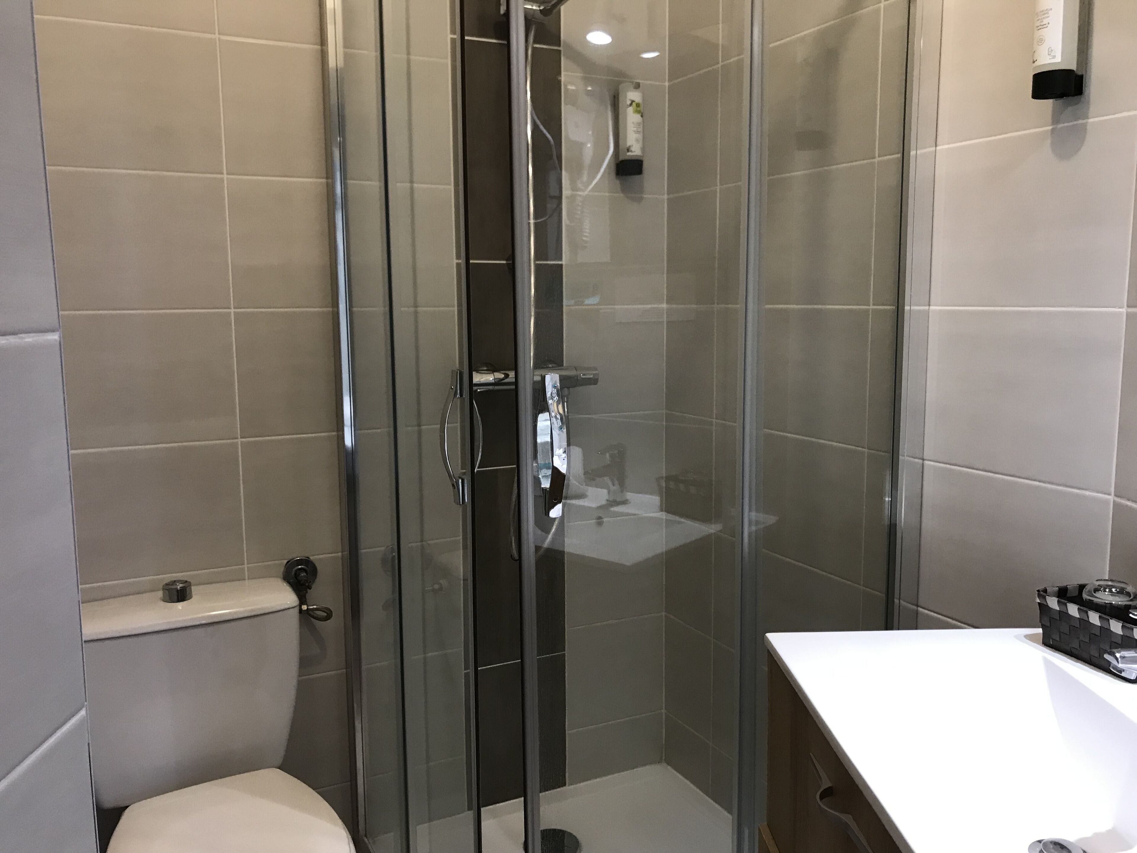 Une salle de bain moderne avec une douche à parois de verre, des toilettes et un lavabo blanc.