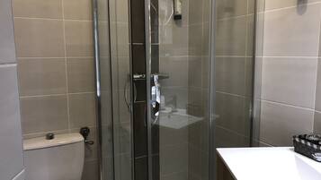 Une salle de bain moderne avec une douche à parois de verre, des toilettes et un lavabo blanc.