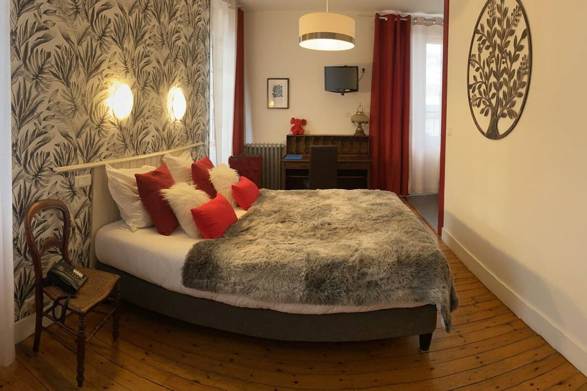 A bedroom with a bed, a chair, a desk, and a television.
