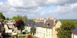 A historic town with stone buildings, a prominent castle-like structure in the background, and a lush green landscape. - Hôtel Belle Vue (Coucy-le-Chateau-Auffrique)
